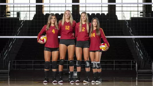 USC Women's Volleyball seniors Victoria Garrick, Brittany Welsh, Madison Murtagh, and Reni Meyer-Whalley stand in front of a net.