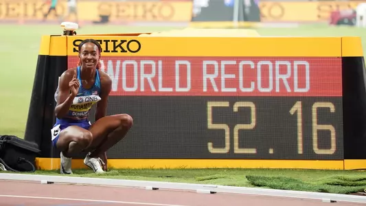 Dalilah Muhammad next to scoreboard showing world record