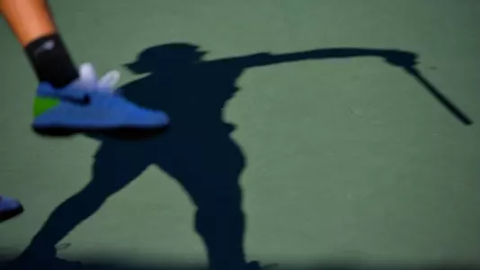 A player's shadow reflects his forehand shot on the courts of Marks Stadium