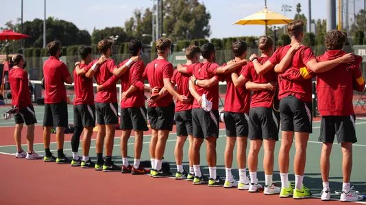 USC players line up for the National Anthem with  arms around each other