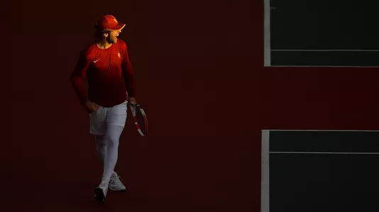 Stefan Dostanic smiles across the net with the sun on hist face during a match at Marks Stadium