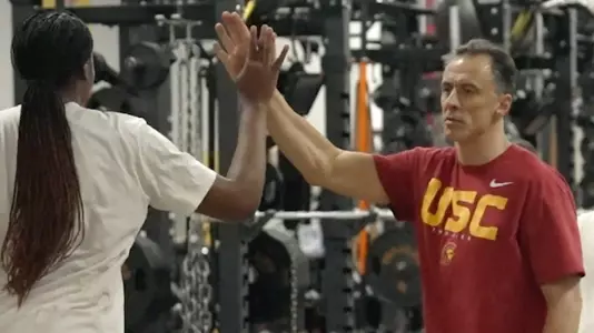 Nik Popovic give a player a high five during a women's basketball training session