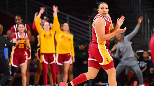 Destiny Littleton claps after making a 3-pointer against UCLA at Galen Center, with teammates celebrating on the sideline.
