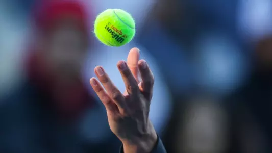 A USC player's hand rises up to toss the ball for a serve