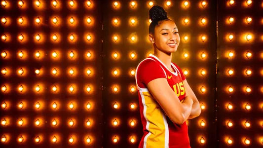 JuJu Watkins smiles in front of a wall of lights
