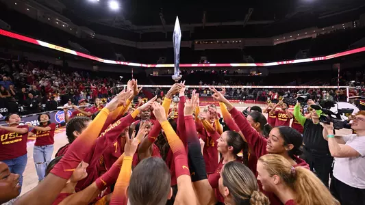 USC women's volleyball team celebrates a win over No. 11-ranked Oregon in a huddle with Rylie McGinest holding the sword.