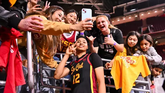 JuJu Watkins takes photos with fans after a game at Galen Center