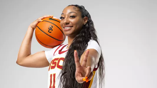 Kennedy Smith looks at camera while holding a basketball on her shoulder.