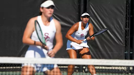 Dani Borruel and Lily Fairclough await a serve at the tennis net.