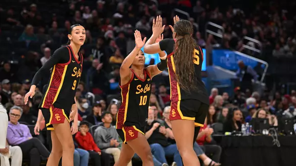 Trojan wbb players high five after a win