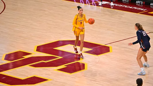 Jazzy Davidson brings the ball down the court in a gold jersey.