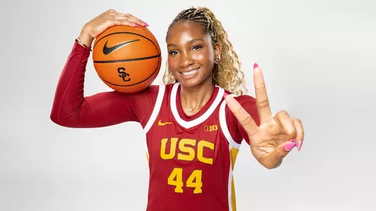 Kiki Iriafen holds a basketball and shows Fight On during a photo shoot