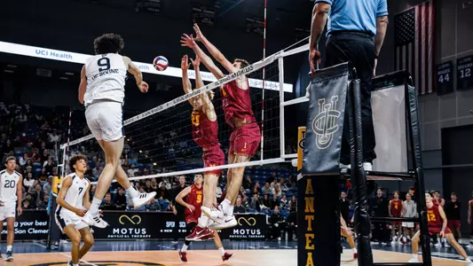 Two USC men's volleyball players go up to block an attack by a UC Irvine player during a match at Bren Events Center in Irvine.