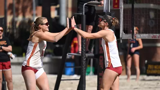 USC beach volleyball sophomore Zoey Henson and junior Madison White high five at midcourt