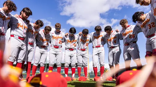 Team photo of the USC Baseball team huddled before a game.