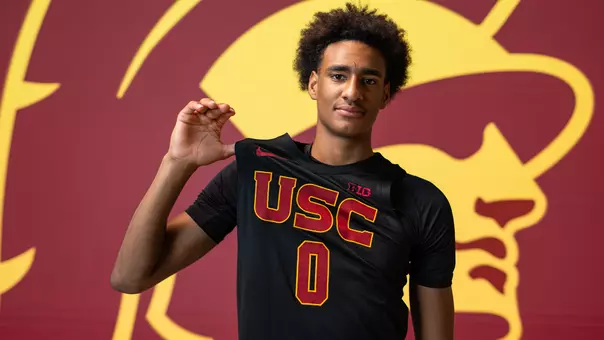 Alijah Arenas holds a basketball and victory sign.