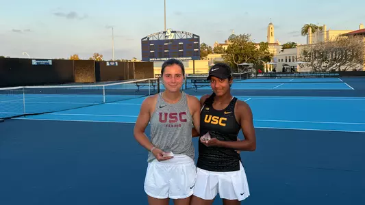 Genie zozaya and Krisha Mahendran pose with trophies on tennis court.