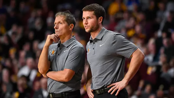 Eric Musselman and Michael Musselman talk on the sidelines during a game at Minnesota