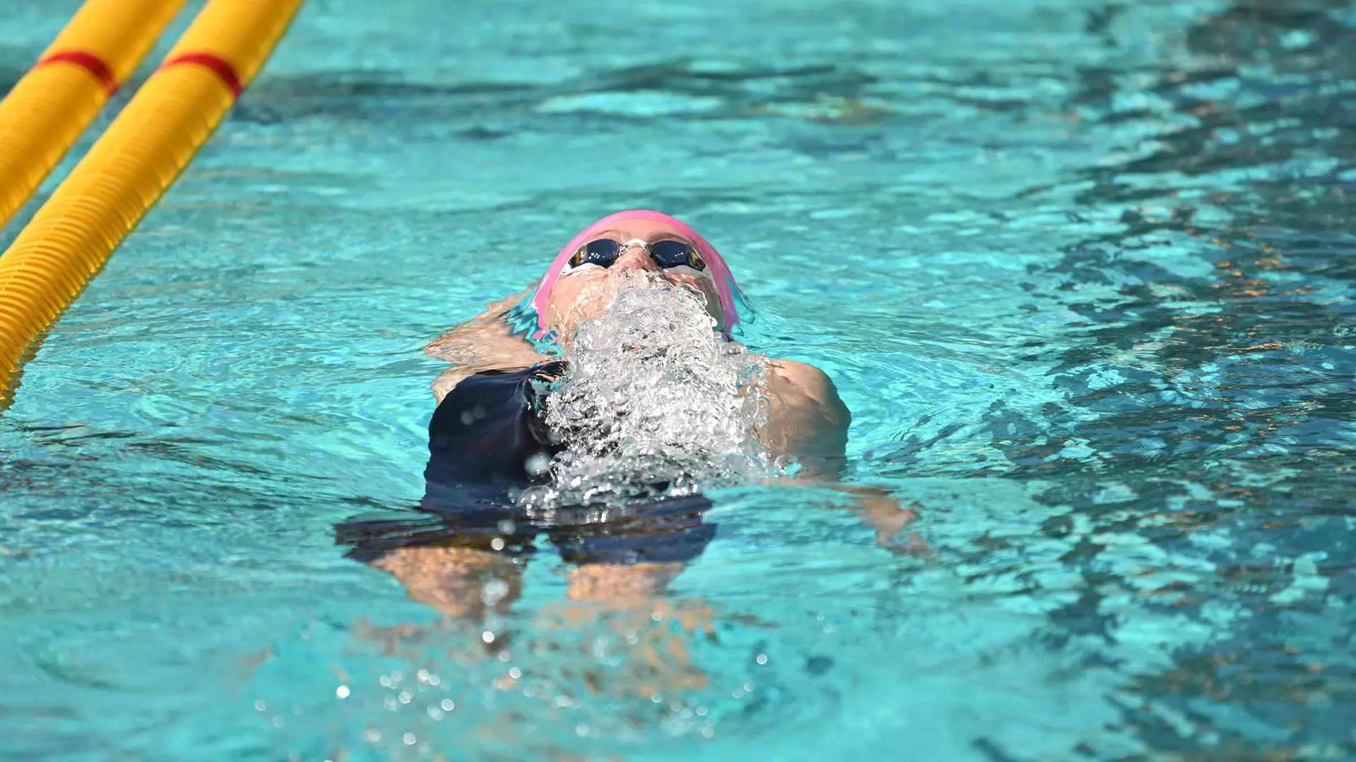 USC Swimmer breaking through the water on her back.