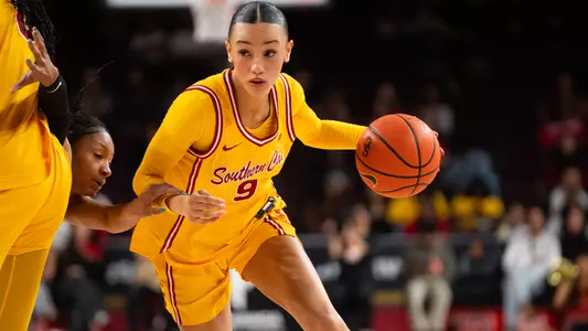 Jazzy Davidson attempts to drive past a defender on basketball court.