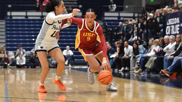Jazzy Davidson drives with basketball while holding off a defender.
