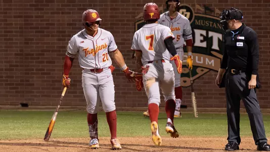 Abbrie Covarrubias high fives Isaac Cadena after scoring a run in the Trojans Thursday night win at Cal Poly.