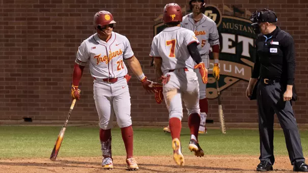 Abbrie Covarrubias high fives Isaac Cadena after scoring a run in the Trojans Thursday night win at Cal Poly.
