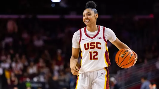 JuJu Watkins smiles while dribbling a ball