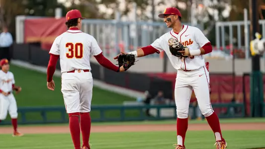Adrian Lopez gives Mason Edwards a high five while walking out onto Dedeaux Field.