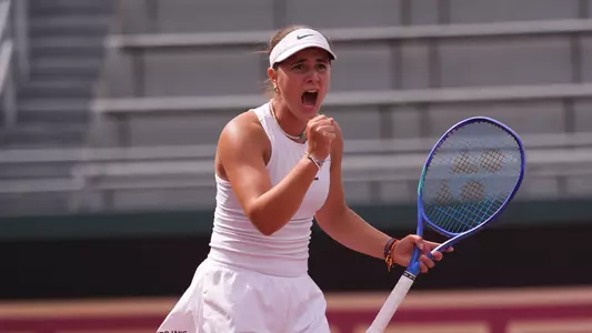 Eugenia Zozaya clutches her fist in celebration while holding a tennis racket.