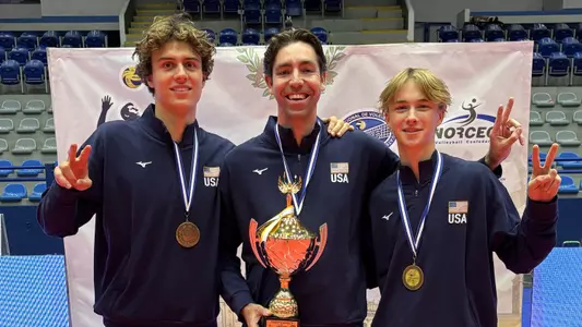 USC men's volleyball outside hitter Blake Fahlbusch, associate head coach Rory Prager, and libero Johnny Dykstra pose with gold medals and the trophy after helping the U.S. Men's U21 National Team win the 2026 Pan American Cup championship in Guatemala City.
