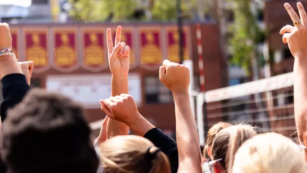 USC beach volleyball players with their hands up in the Victory V signal