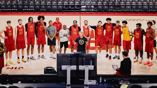 The USC men's basketball team gathers around a television set during a summer practice in the Galen Center