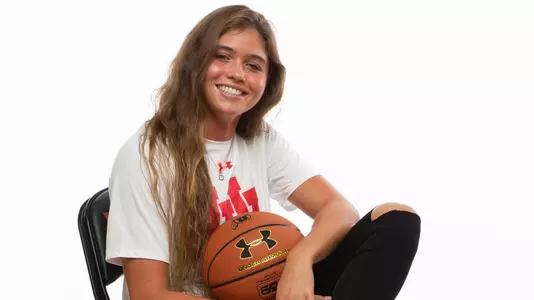 Kemery Martín sits in a chair holding a basketball.