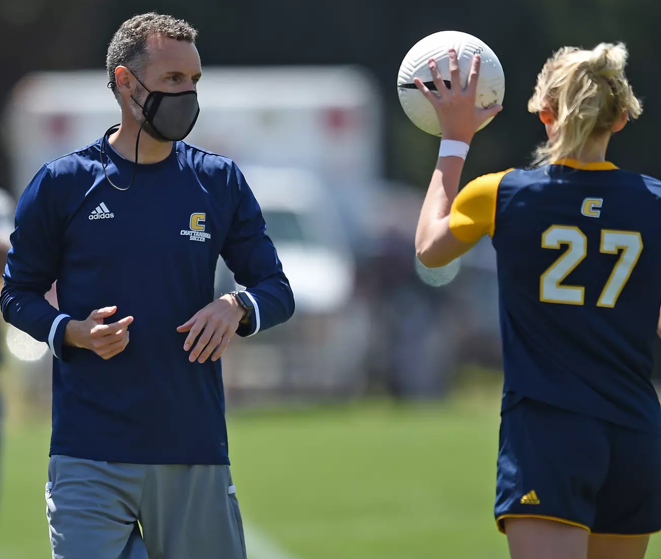 Head Coach Gavin McKinney tosses the ball to Kendra Mueller for the throw in.
