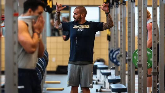 Gerry Pacitti directs football workout in the weight room.