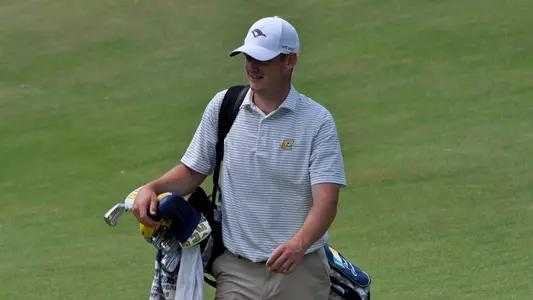 Paul Conroy lets out a wry smile as he carries his bag to the green and looks at a short birdie putt to come.