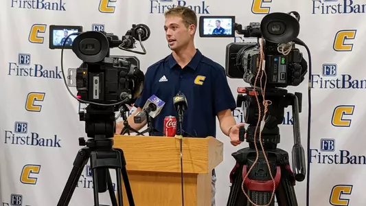 Preston Hutchinson is behind the podium speaking to the media at weekly press conference.