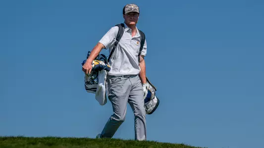 John Houk carries his clubs over a hill as he strides toward his next shot at Erin Hills.
