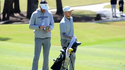 Garrett Engle ponders next shot alongside Coach Blaine Woodruff who is reading his yardage book.