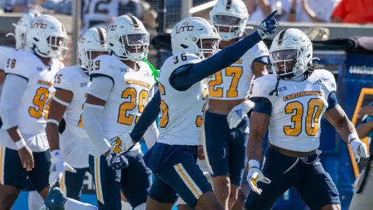 D'Arco Perkins-McAllister points towards sideline leading a rush of teammates celebrating a pick.