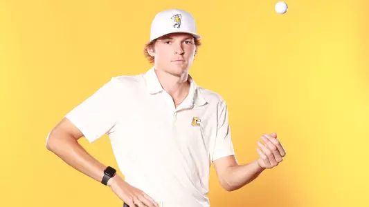 Carson Johnson poses on content day with a serious stare in the camera with a golf ball lofted from his left hand