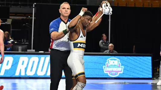 Isaiah Powe flexes as his hand is raised after winning the 161st SoCon Championship in Chattanooga Mocs history