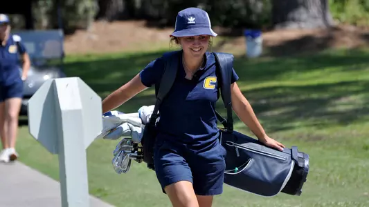 Violeta Fernandez-Tagle carries her bag with a wry smile heading to the 13th tee at the SoCon Championships