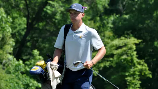 Garrett Engle carries a stern look along with his bag as he strides toward the green at the NCAA Auburn Regionals