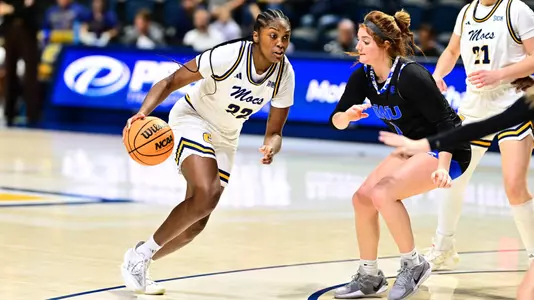 women's basketball player with the basketball, driving toward the basket with a defender in front of her.