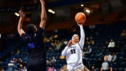 women's basketball player shooting a floater with a defender jumping in front of her.
