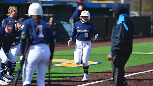 softball player running toward home after hitting a home run