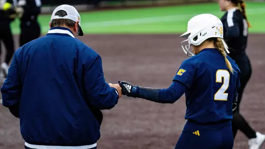 softball player congratulated by coach at first base