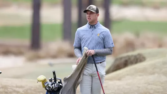 Garrett Engle cleans his iron and stares ahead at the green after his approach at Mid Pines.